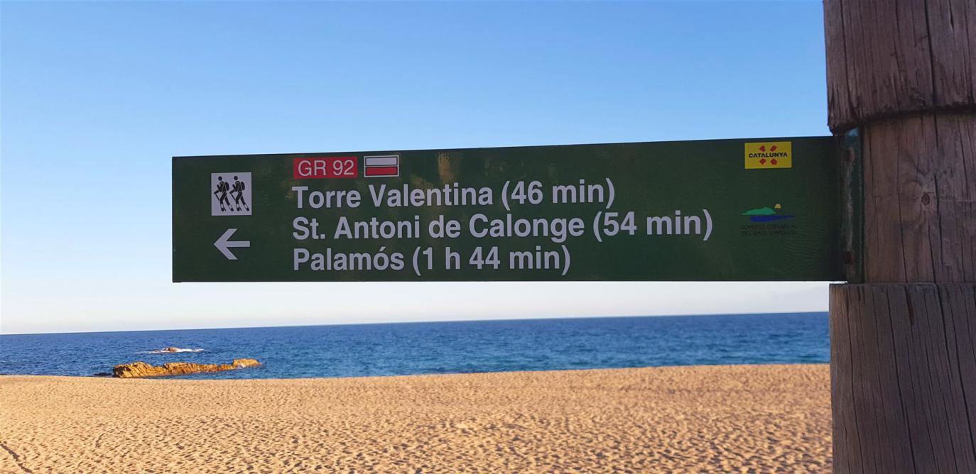 Wegweiser am Strand mit Zeitangaben